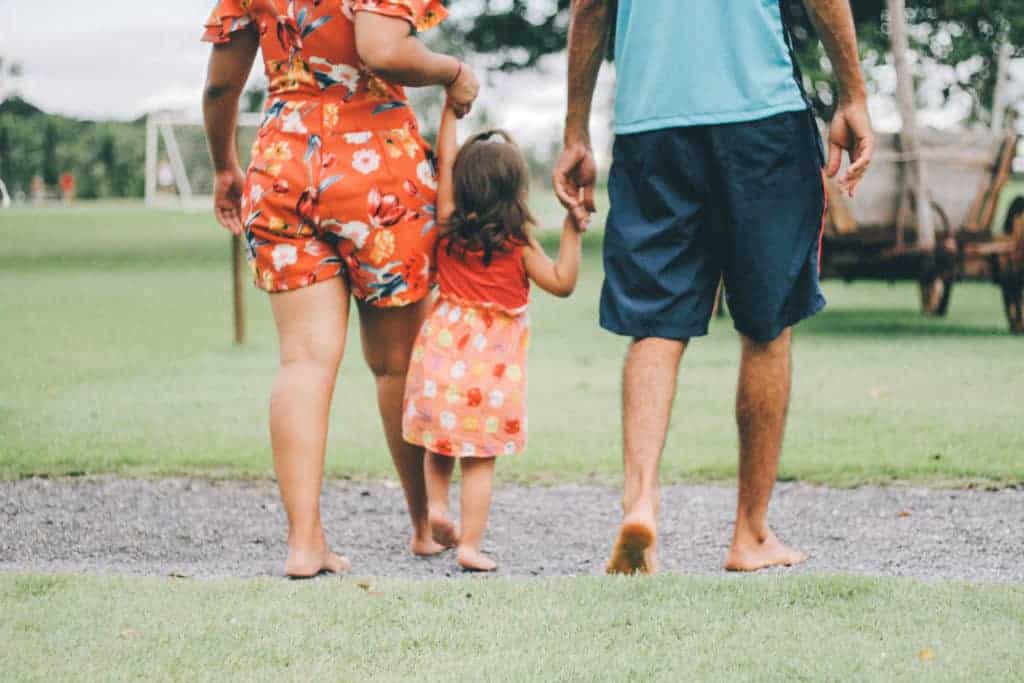 a man and a woman holding hands walking with a little girl.