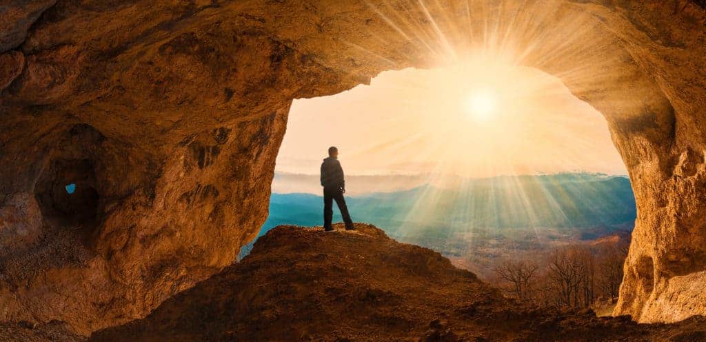 Man in cave looking at sunset