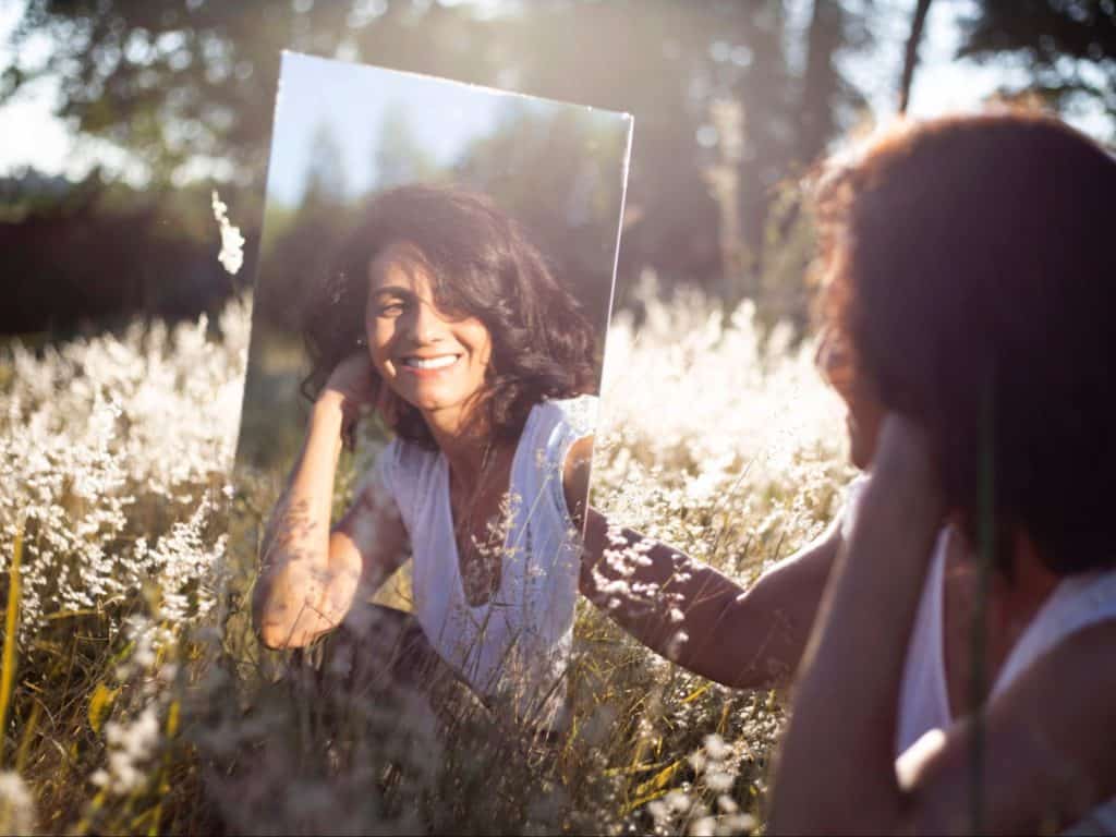Woman in field thinking of her boundaries, and in the mirror