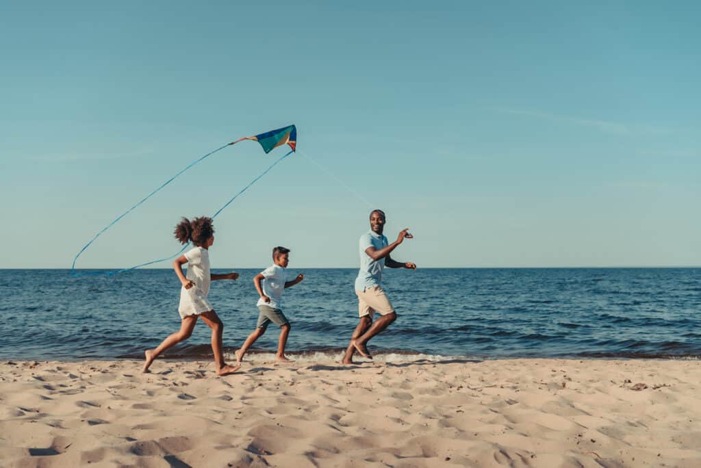 a group of people running on a beach with a kite.