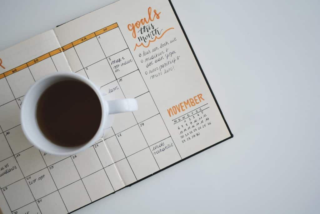 white ceramic mug with coffee on top of a planner S.M.A.R.T. Goal