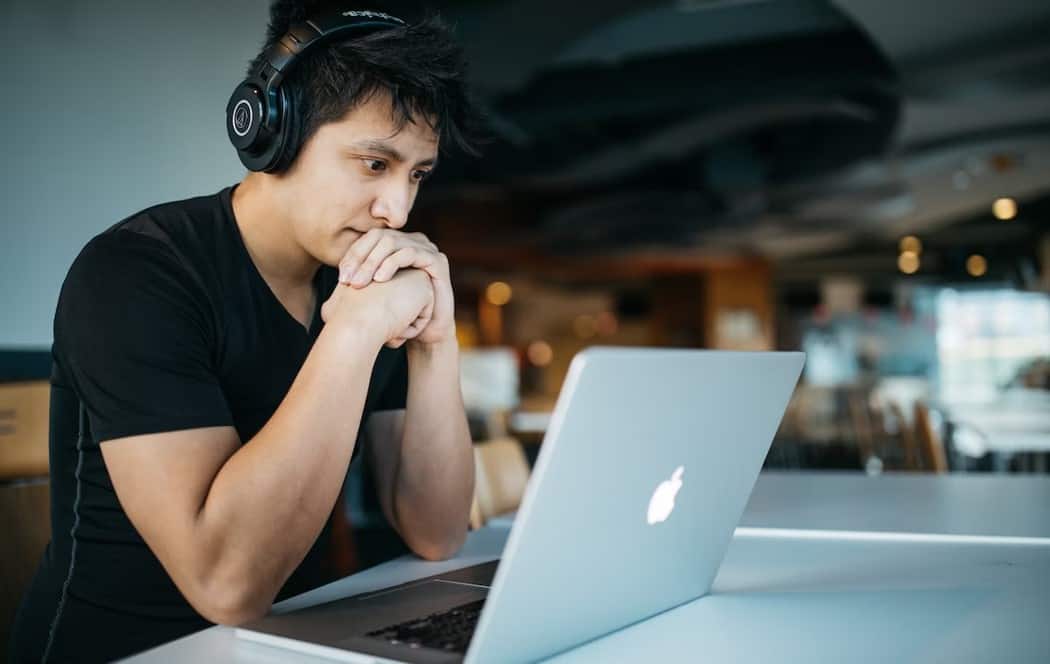 a man wearing headphones looking at a laptop.