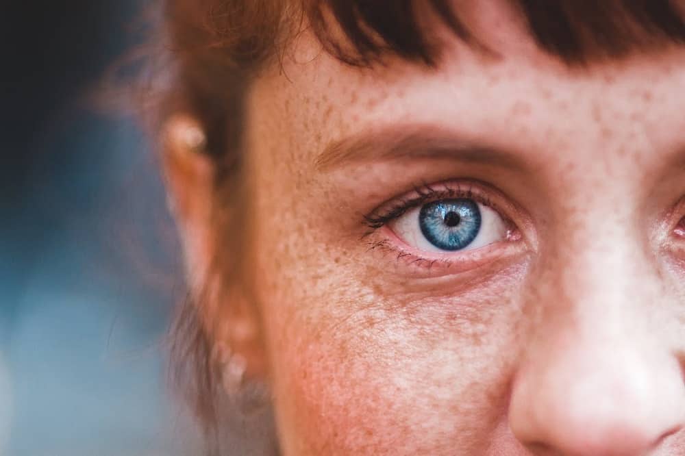 a close up of a woman with freckled eyes.