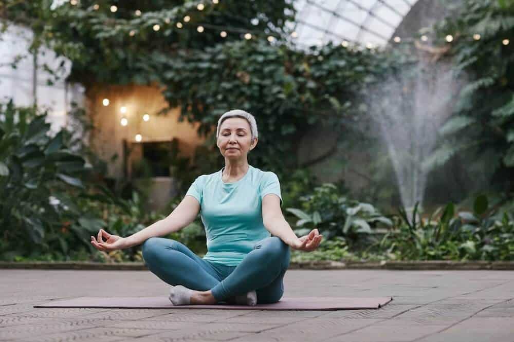 a woman is meditating in a greenhouse.
