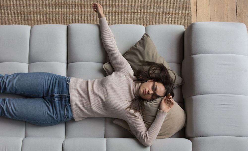 A woman experiencing the Sunday Scaries, laying on top of a couch.