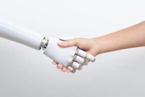 A human hand shakes hands with a robotic hand against a plain white background.
