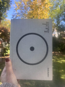 A hand holding the book “The Creative Act: A Way of Being” by Rick Rubin, featuring a large black circle on the cover.
